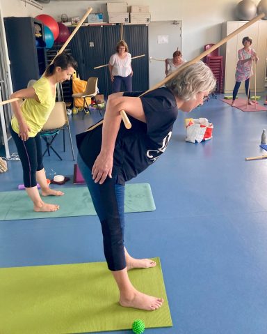 Yoga à Eysines Posture de la demi-pince en yoga avec 2 bâtons pour corriger l'alignement du dos, pratiqué dans la salle de yoga de Eysines